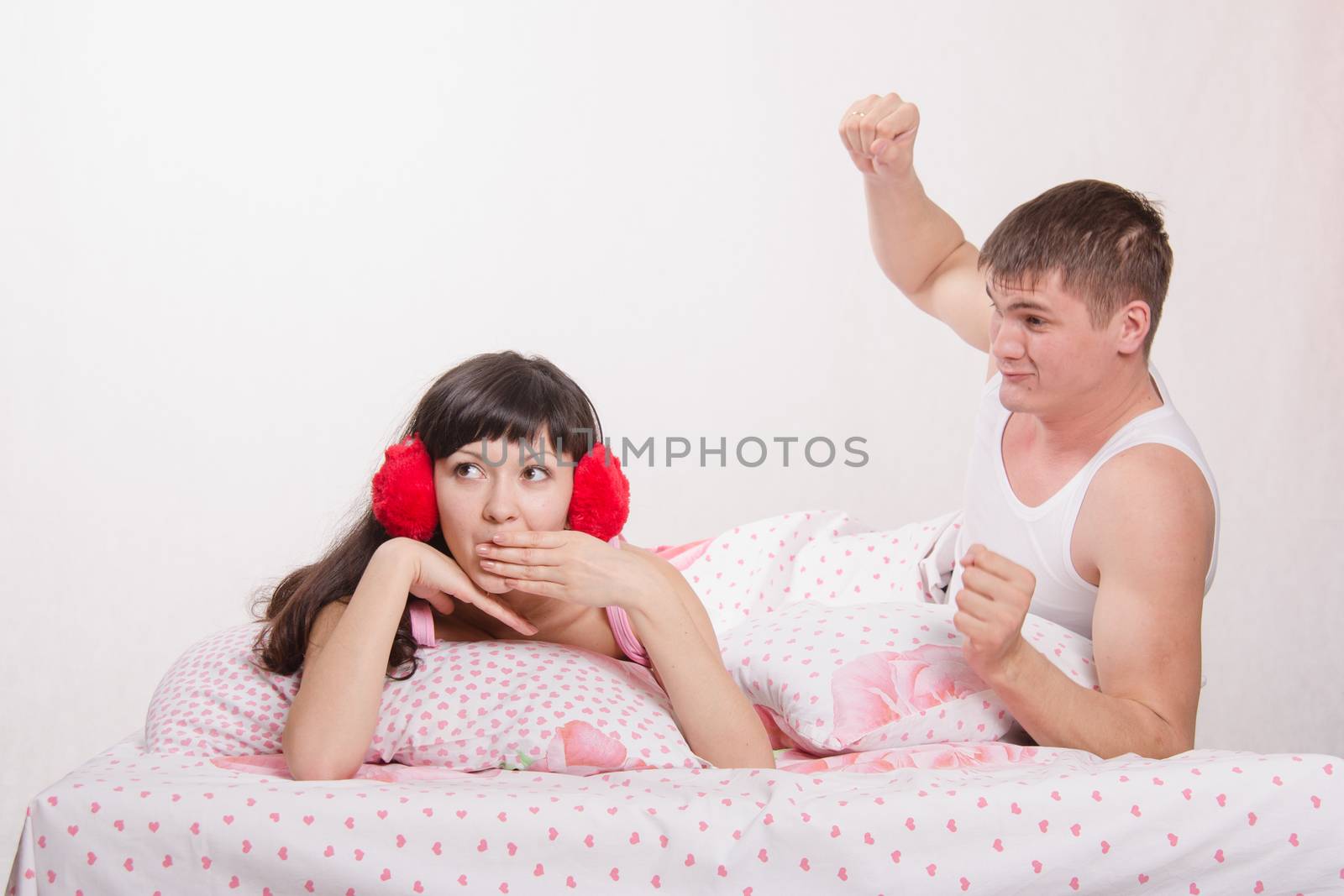 Young family couple quarrels in a bed