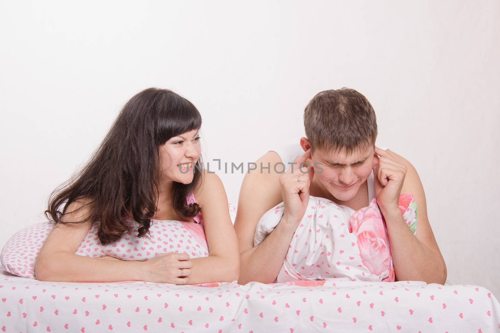 Young family couple quarrels in a bed