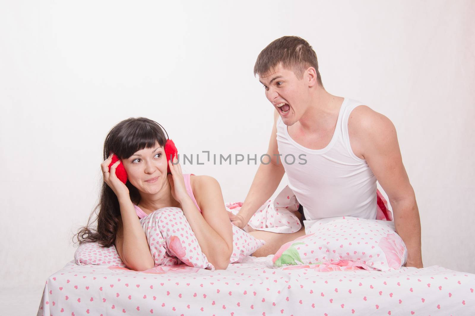 Young family couple quarrels in a bed