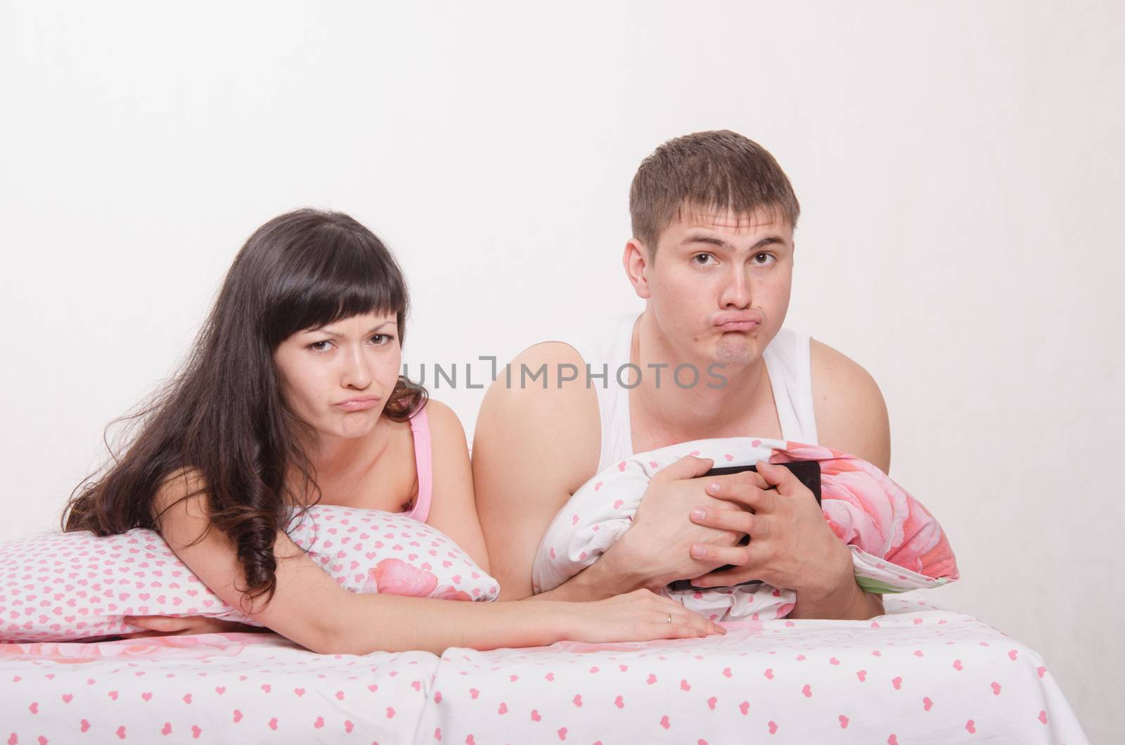 Young beautiful couple watching a movie in the tablet computer while lying in bed