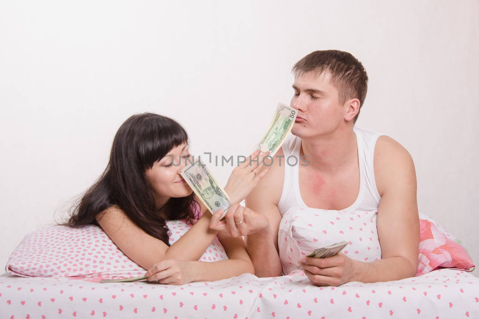 Young couple with money lying in bed