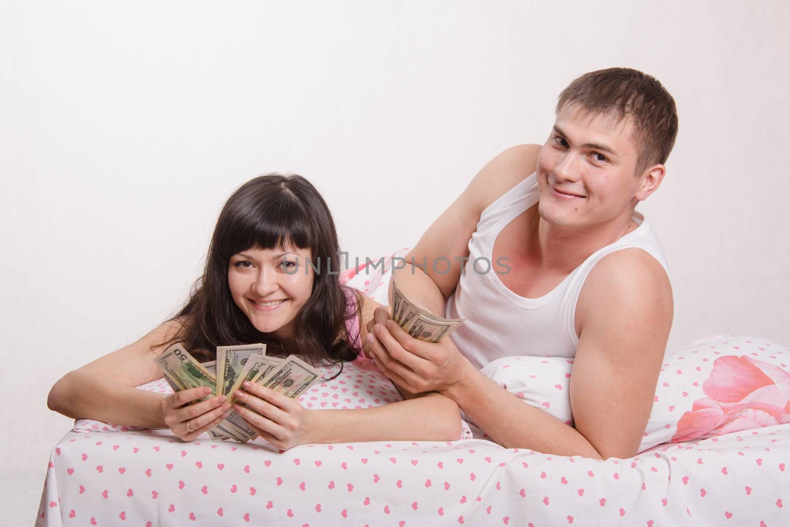 Young couple with money lying in bed