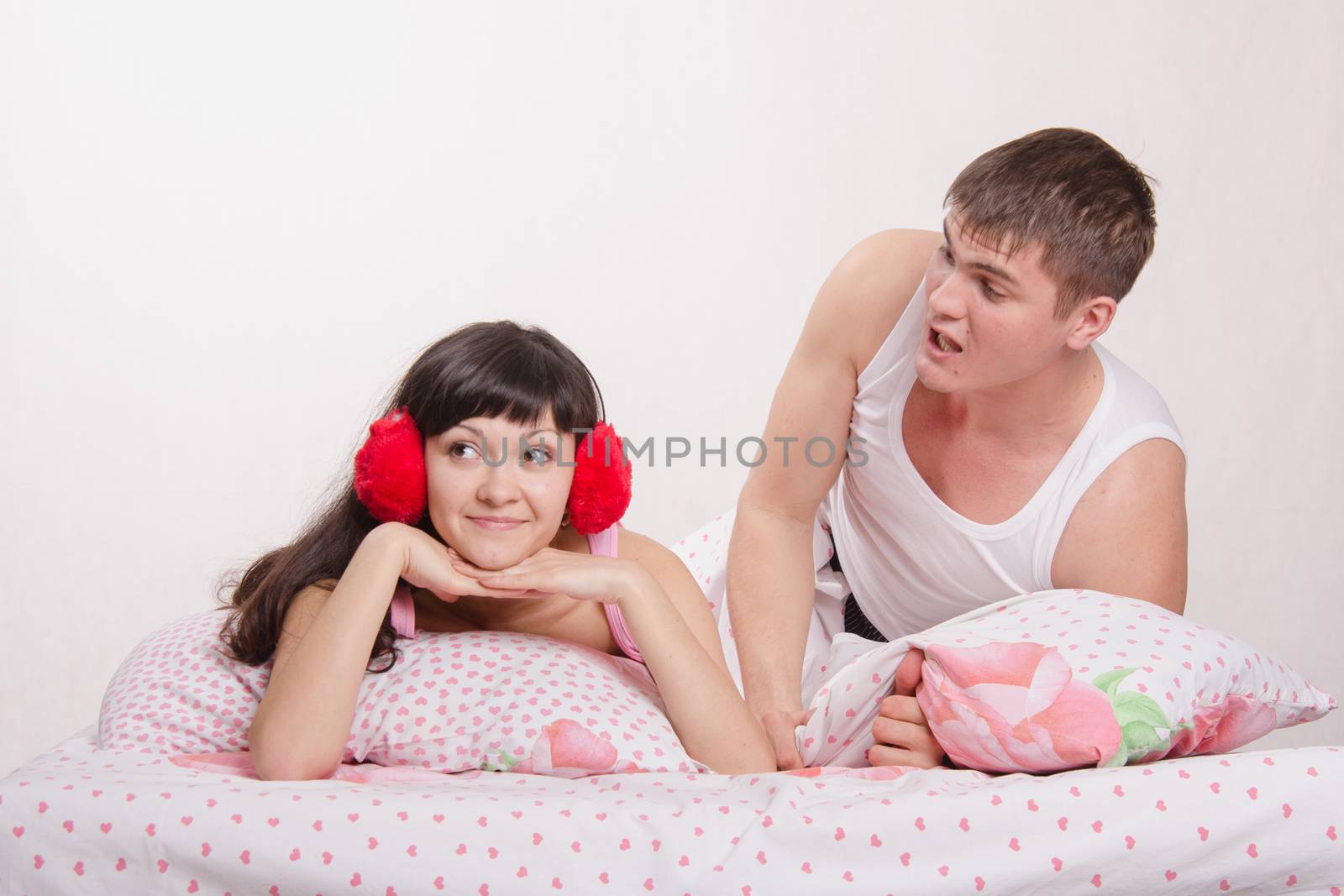 Young family couple quarrels in a bed