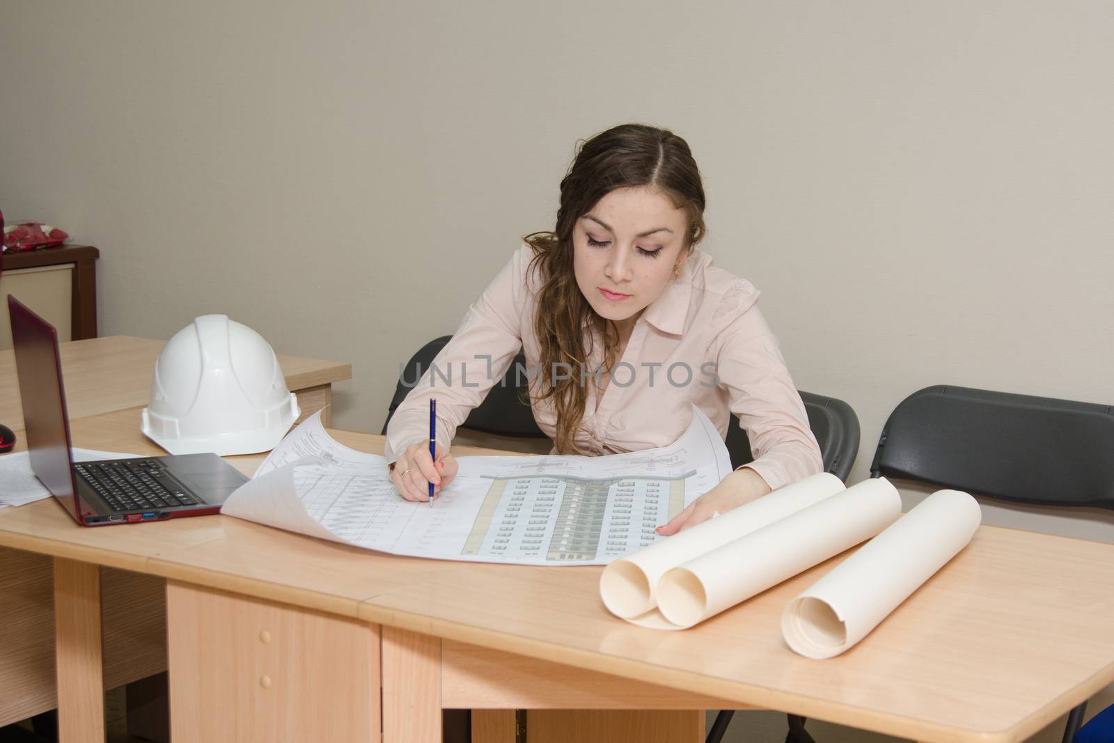A young girl in a helmet works at his desk in the office