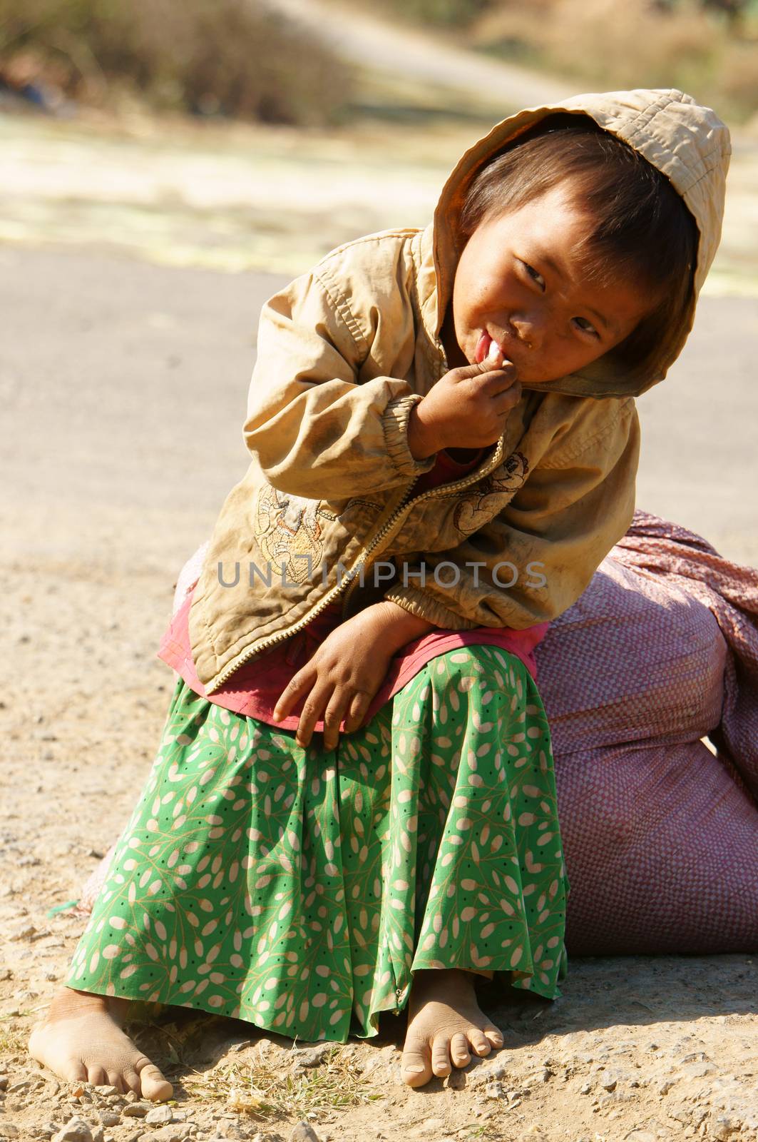 BUON ME THUOT, VIET NAM- FEB 7:Unidentified Asian children sitting on pavement, Vietnamese kid hungry and eating, dirty clothing, barefoot, poverty child at poor countryside, Vietnam, Feb 7, 2014