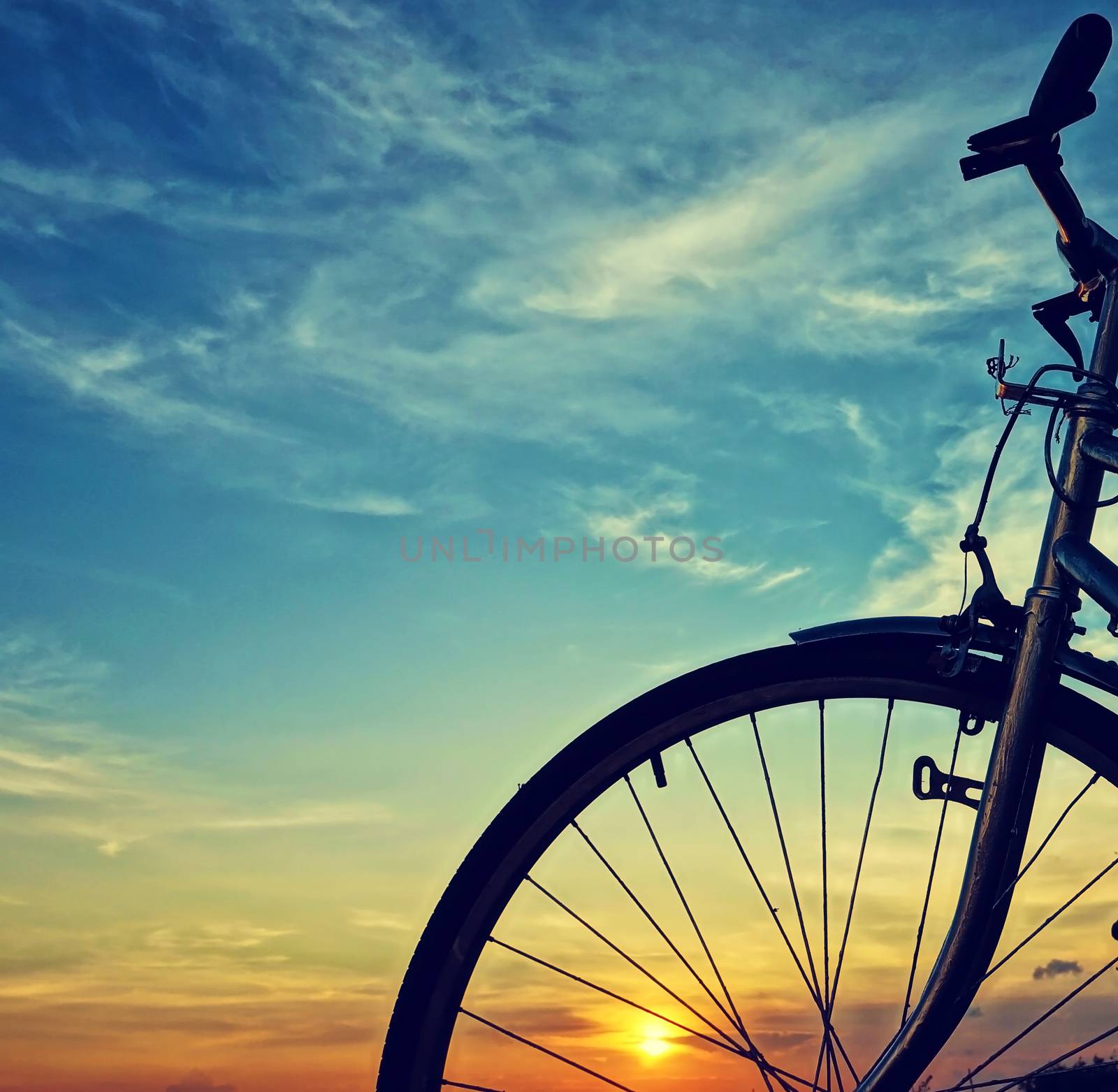 Beautiful close up scene of bicycle at sunset, sun on blue sky with vintage colors, silhouette of bike forward to sun, wonderful rural of Mekong Delta, Vietnam countryside