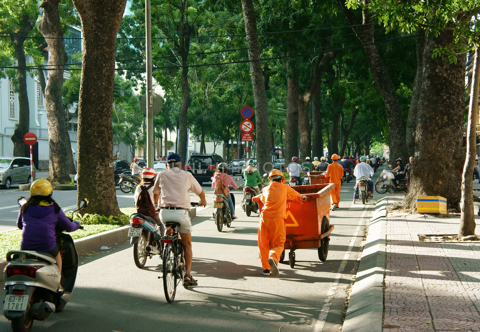 HO CHI MINH CITY, VIET NAM- SEPT 7: Asia city scene at evening, sanitation worker work on road, vehicle as bicycle, motorbike in traffic, Ton Duc Thang street with row of tree, Vietnam, Sept 7, 2014