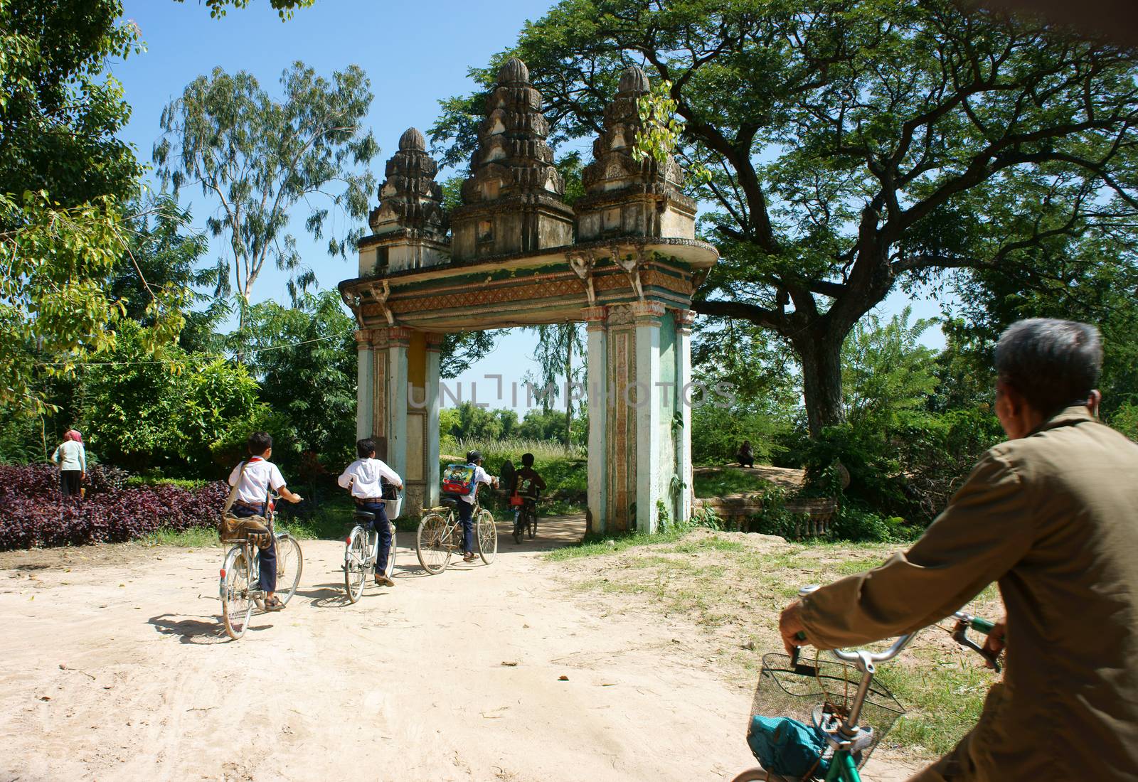 Group Asian kids, riding bike, Khmer village gate by xuanhuongho