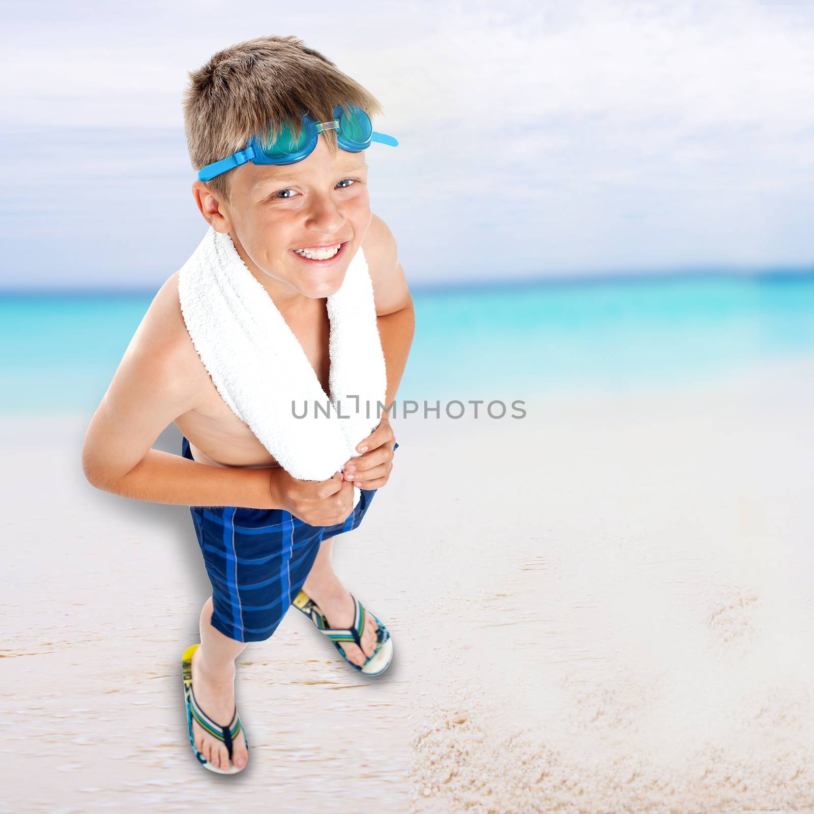 Smiling boy standing on beach background by stockyimages
