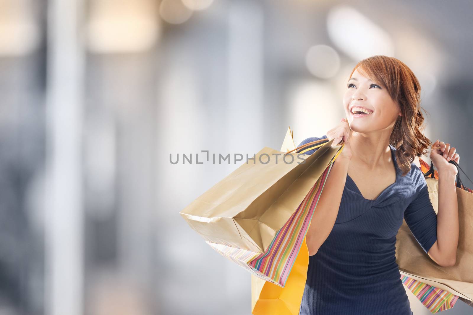 Cheerful shopping woman of Asian holding bags.
