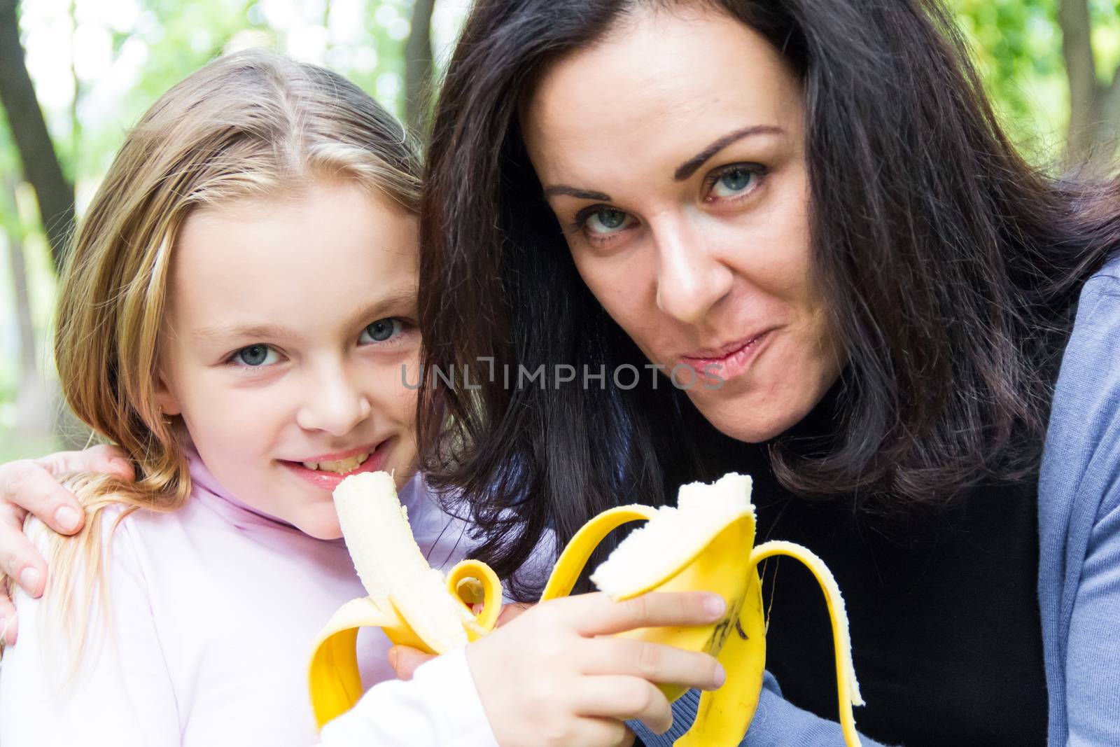 Photo of mother and daughter eating banana