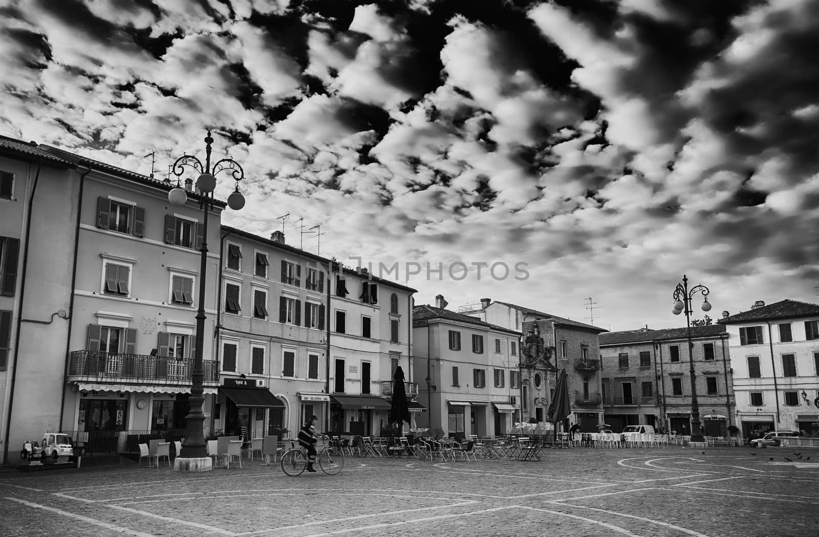 a biker pedals through a central square in a small italian town early in the morning