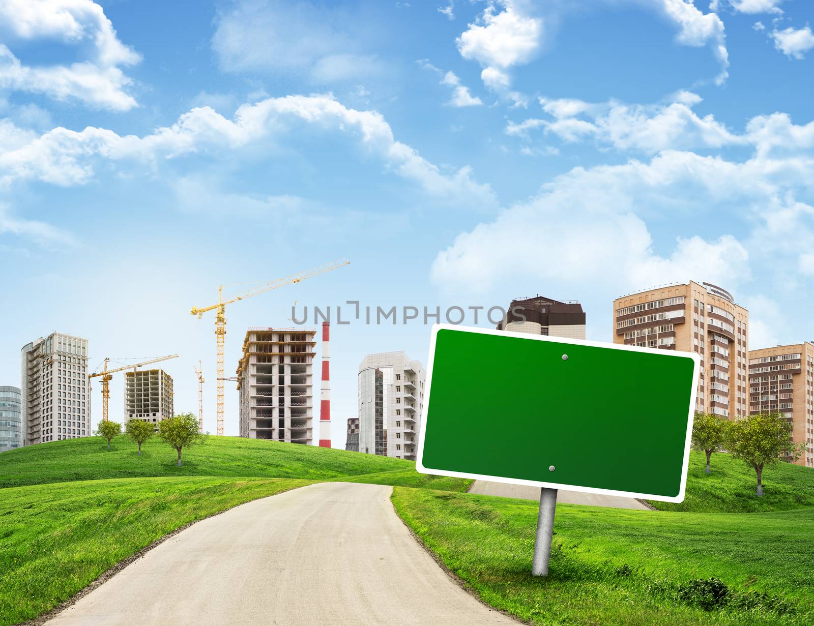 Buildings, green hills and road with empty roadsign against sky by cherezoff