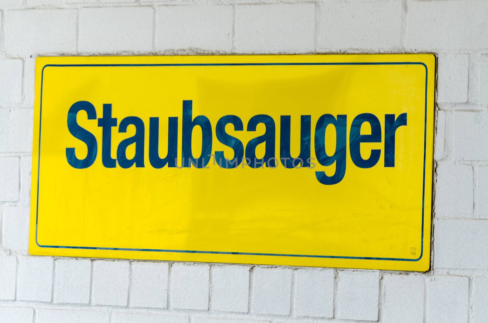 Yellow sign with the words vacuum cleaner on a wall.