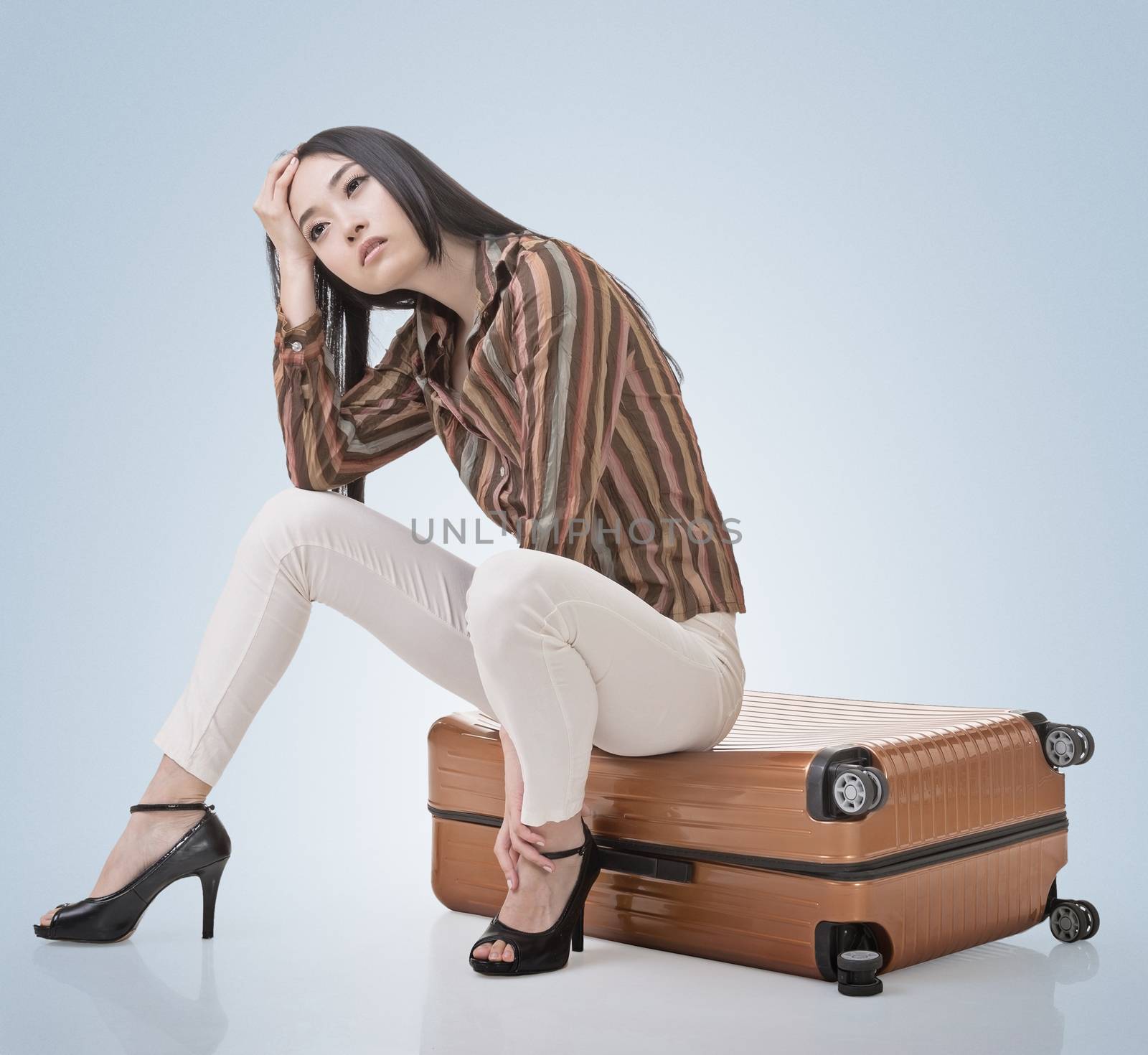 Asian woman thinking and sitting on a luggage by elwynn