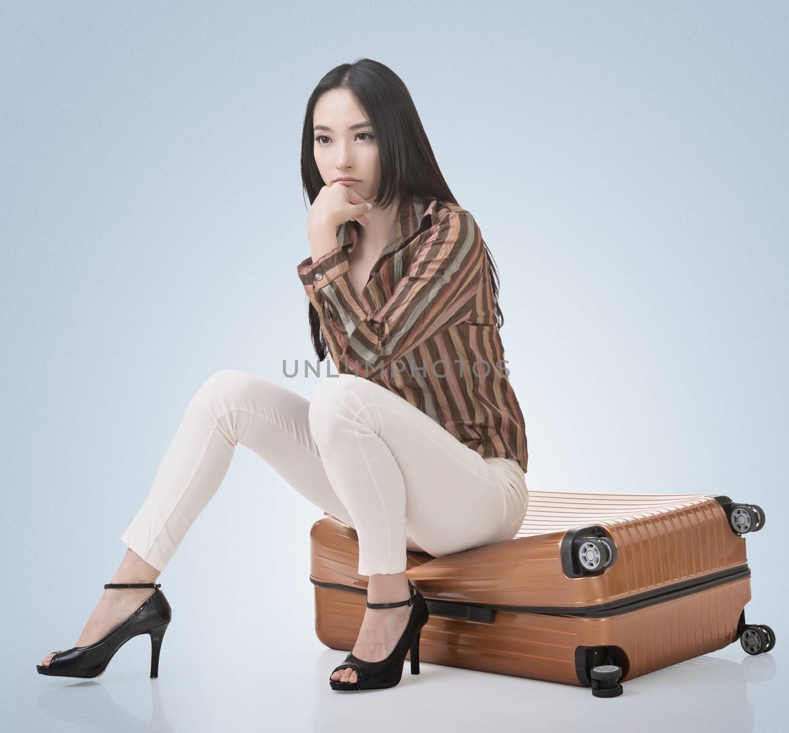 Asian woman thinking and sitting on a luggage in vintage style.