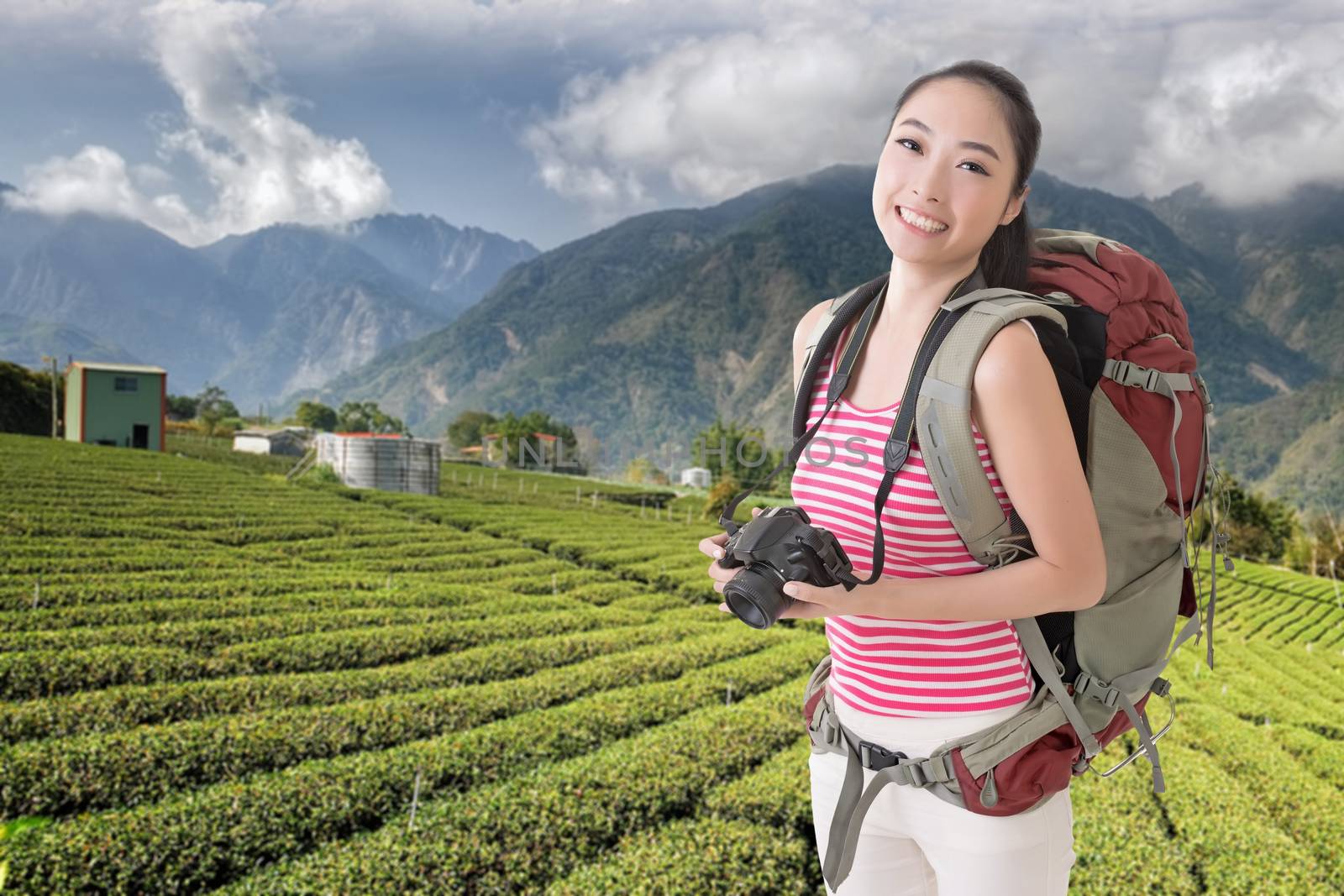 Happy smiling Asian young female backpacker with camera in the countryside.