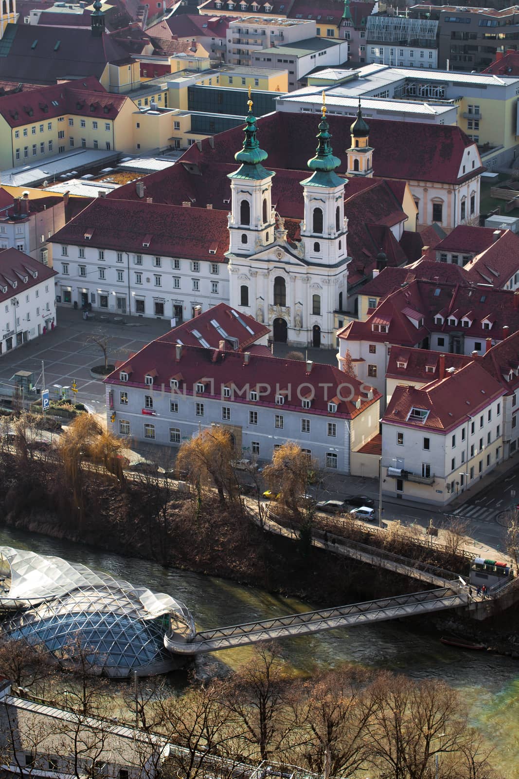 Graz, Austria - January 16, 2011: The Mariahilfer church and Island on Mur river connected by a modern steel and glass bridge, Styria, Graz, Austria