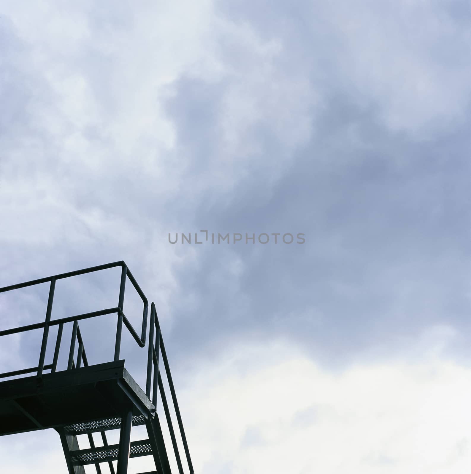 Dark metal staircase and cloudy sky
