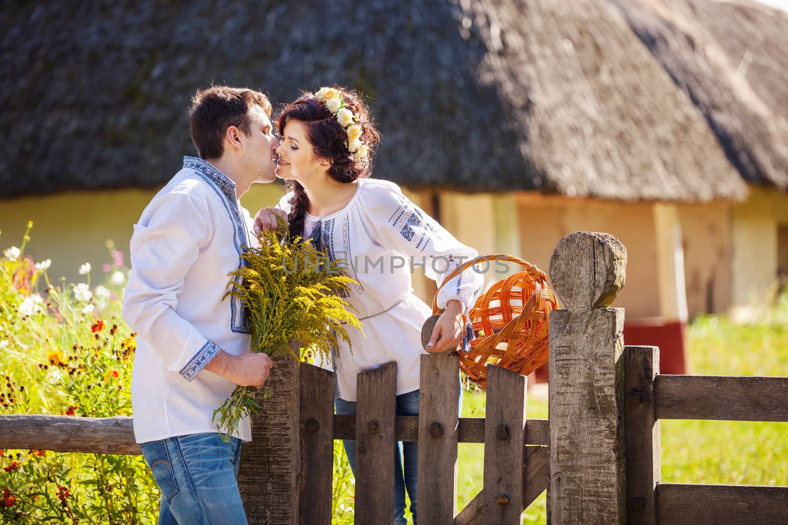 Romantic young couple in Ukrainian style clothes kissing outdoors