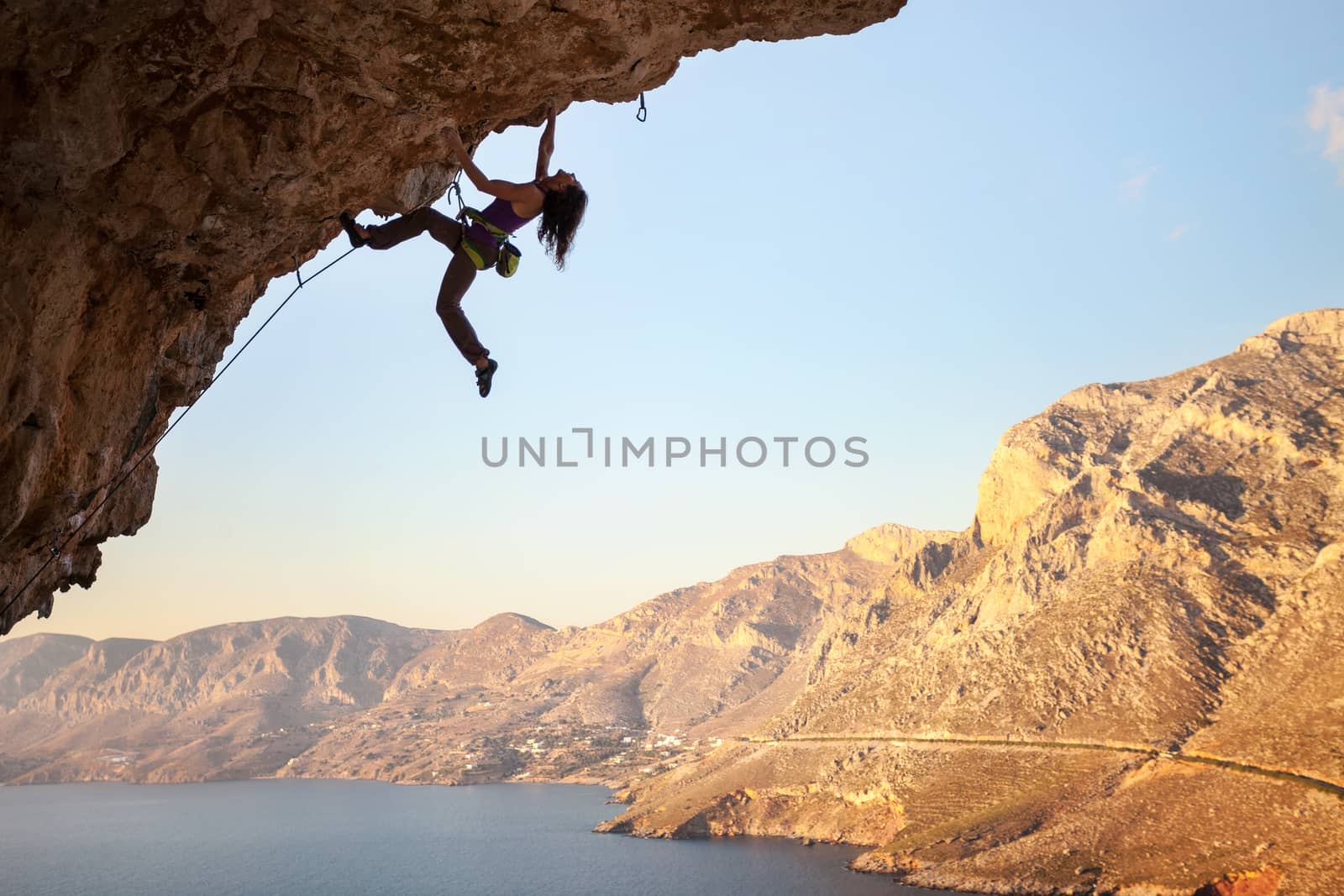 Silhouette of young female rock climber on a cliff by photobac