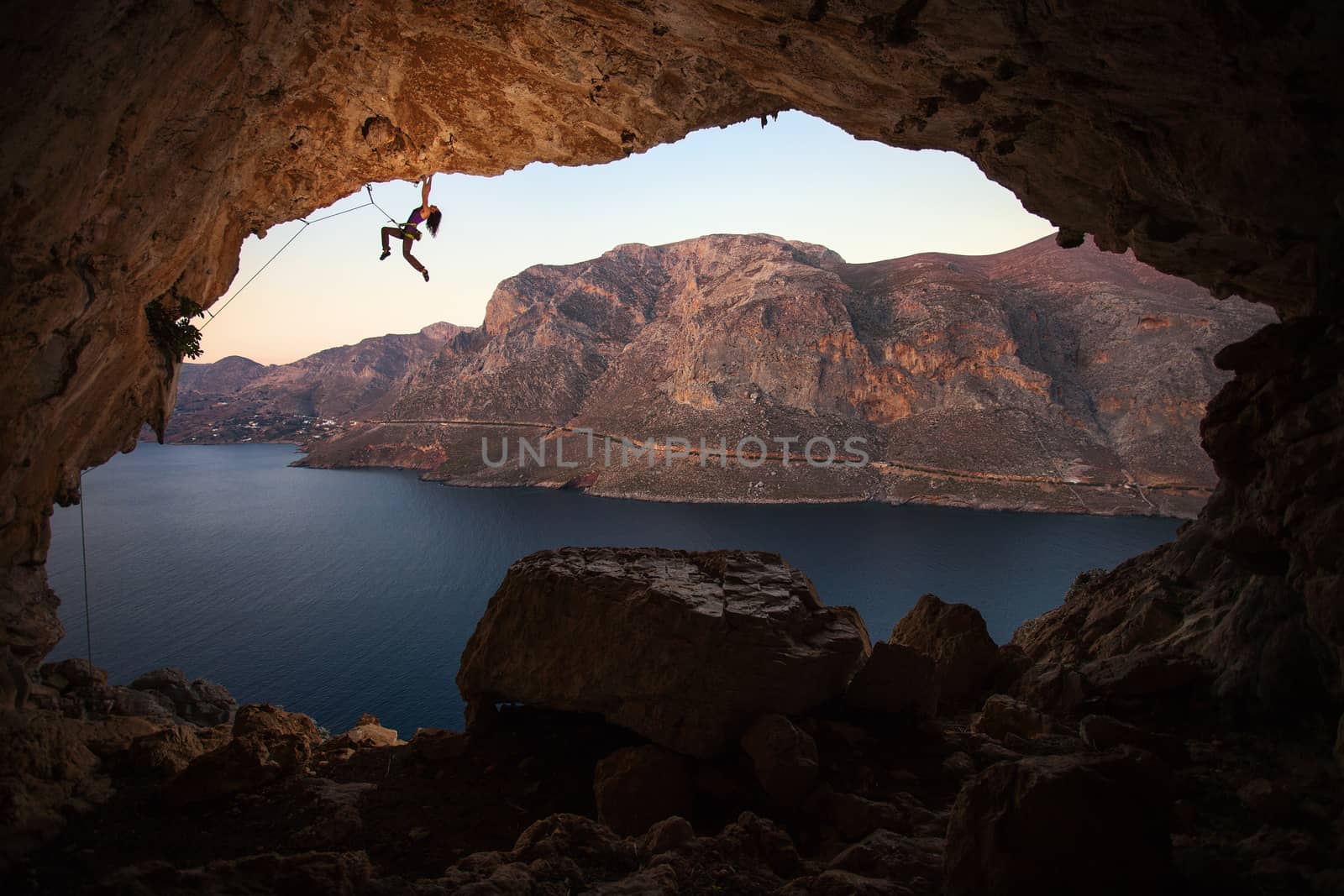 Silhouette of a female rock climber on a cliff in a cave at Kalymnos, Greece