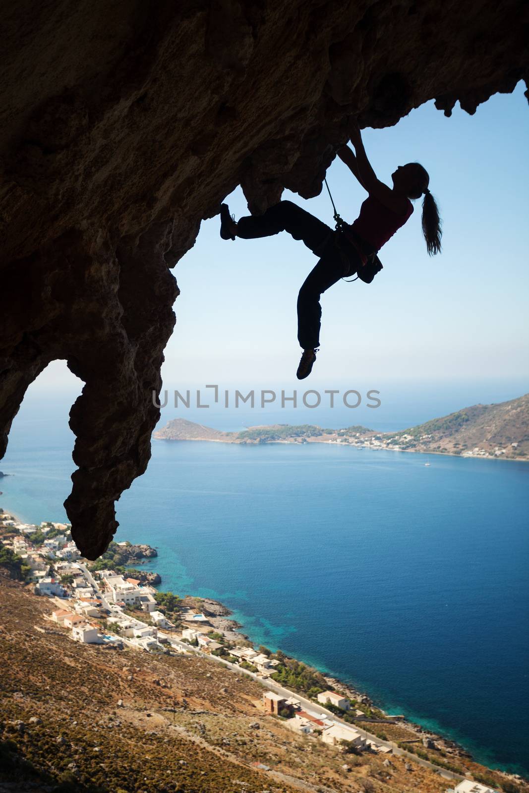 Silhouette of young female rock climber on a cliff by photobac