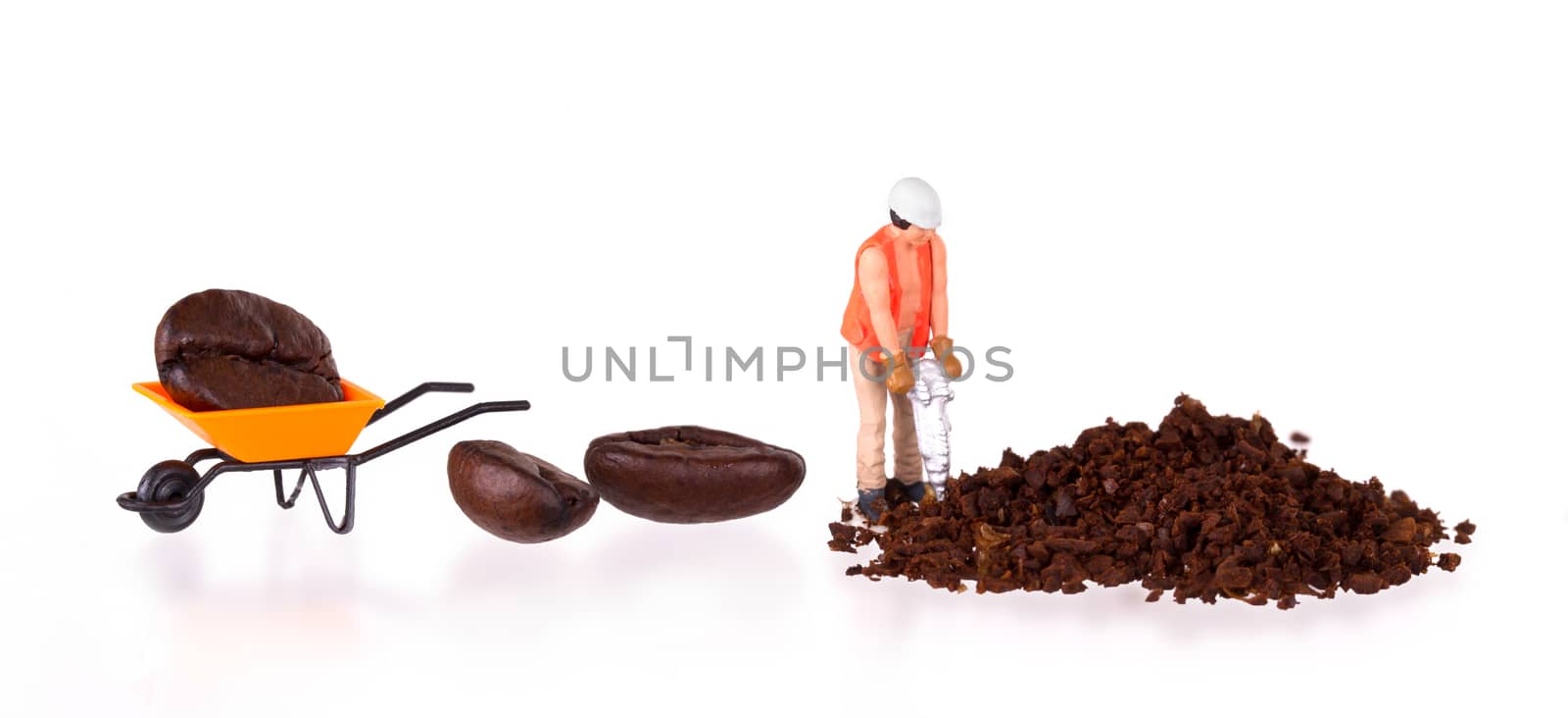 Miniature worker with powerdrill working on a coffee bean