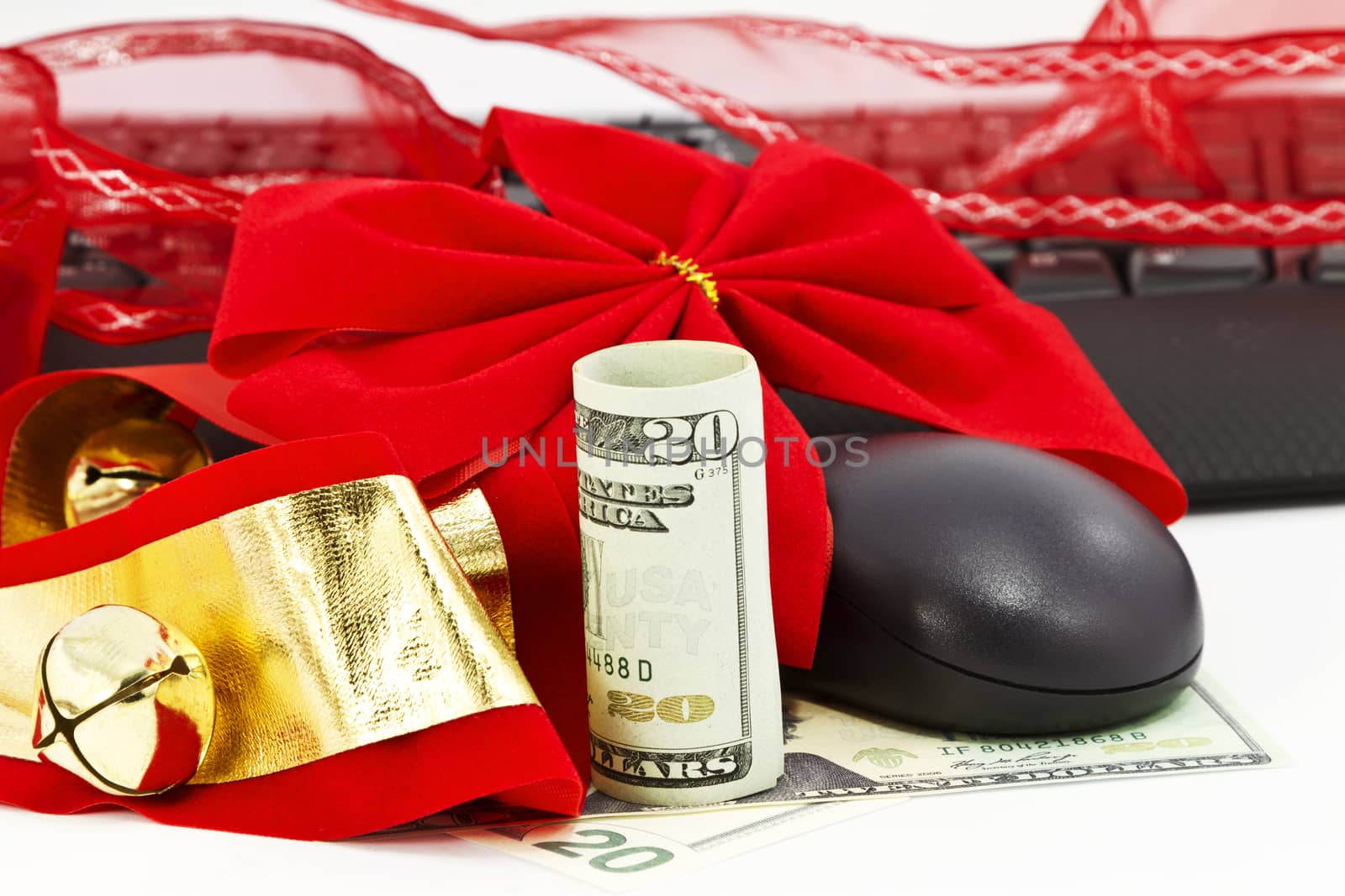 Red ribbon, American currency, and Christmas bells encirle keyboard and mouse.  