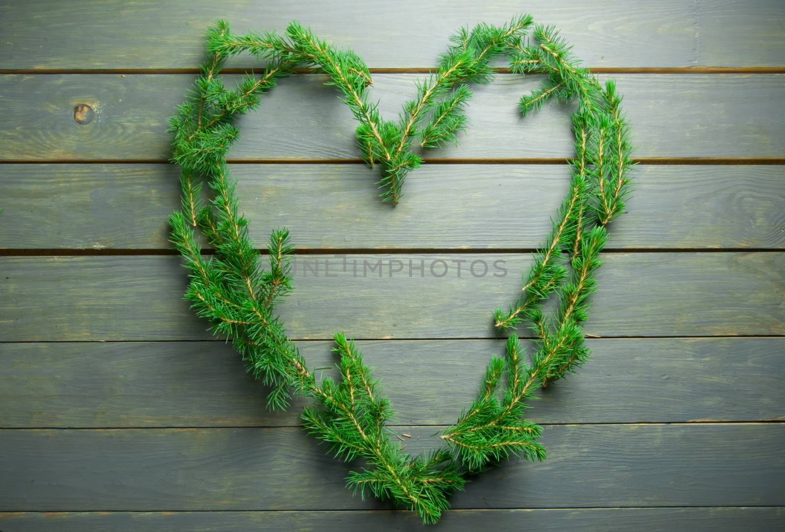 Love heart made with christmas tree fir branches over a wooden background