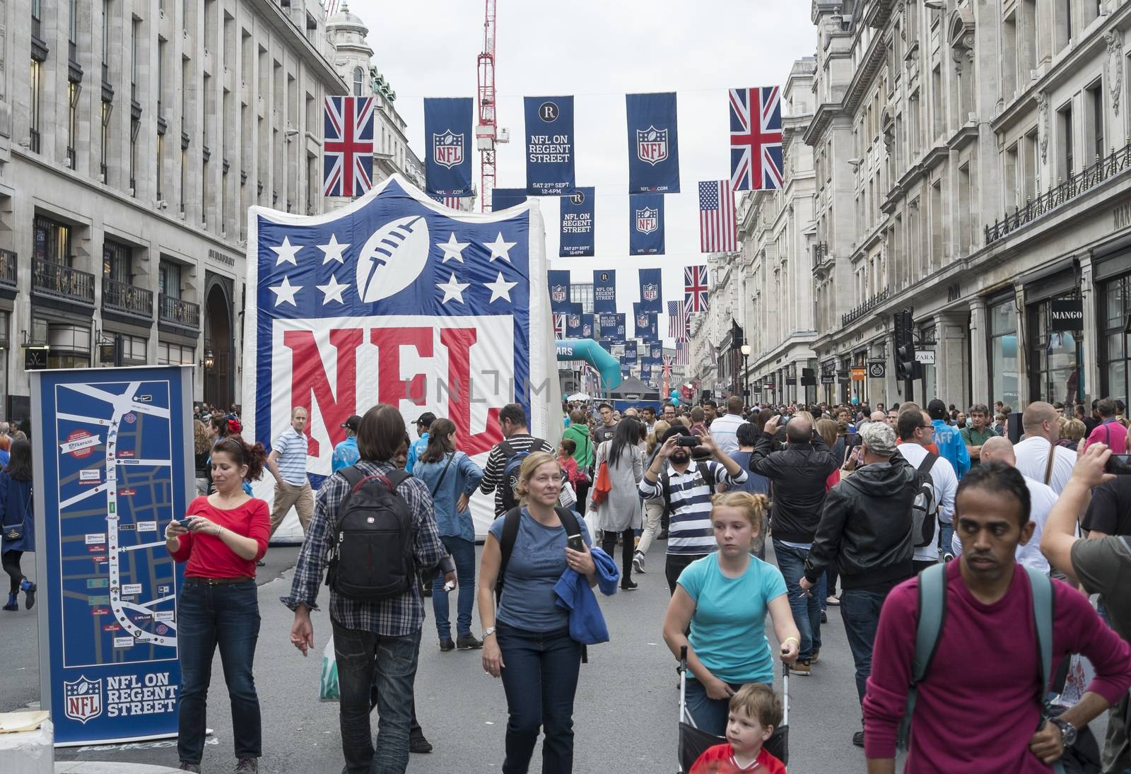 LONDON UK - SEPTEMBER 27: Crowded Regent street with NFL inflatable banners and flags hanging above. September 27 2014 in London. The street was closed to traffic to host NFL related games and events.