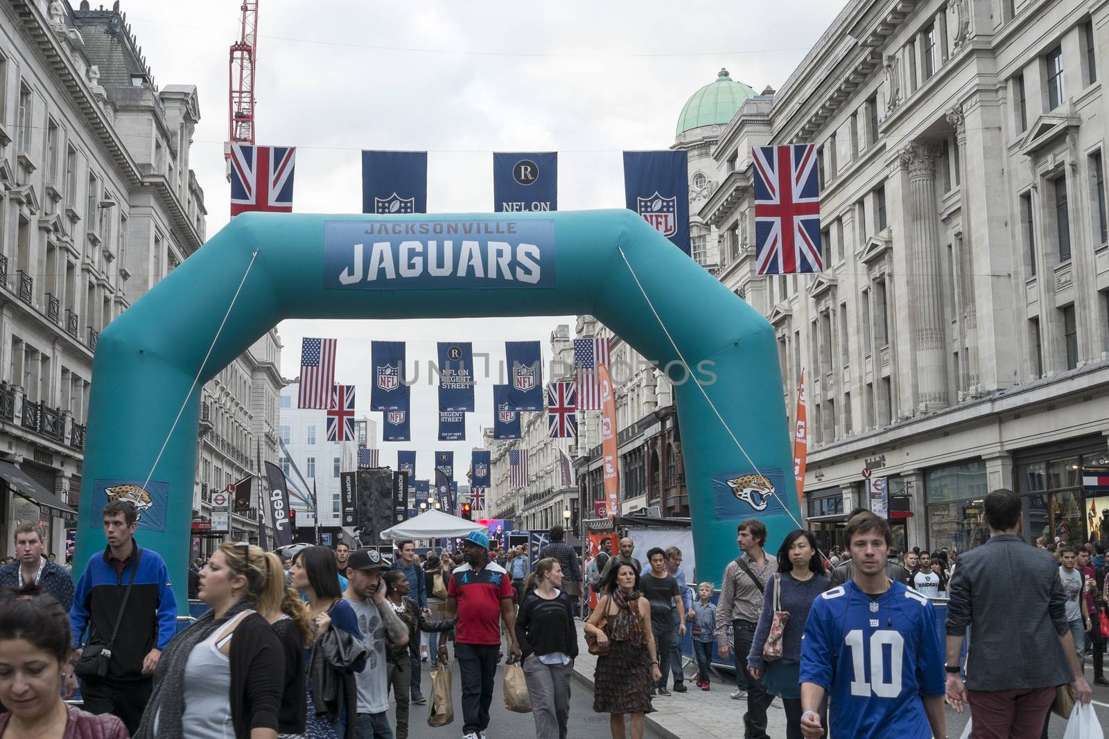LONDON UK - SEPTEMBER 27: Crowded Regent street with Jaguars inflatable arch and NFL flags above. September 27 2014 in London. The street was closed to traffic to host NFL related games and events.