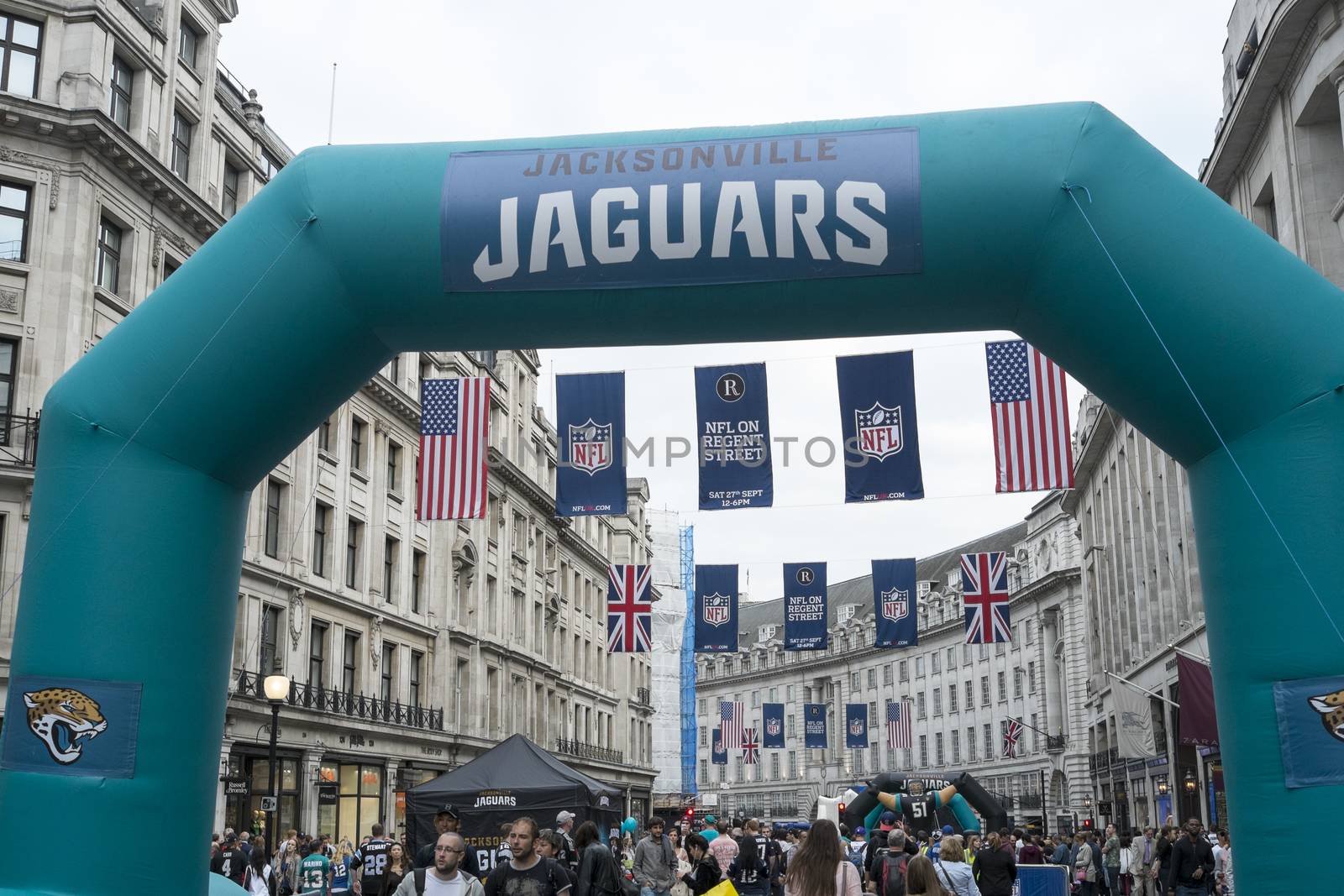 LONDON UK - SEPTEMBER 27: Crowded Regent street with Jaguars inflatable arch and NFL flags above. September 27 2014 in London. The street was closed to traffic to host NFL related games and events.