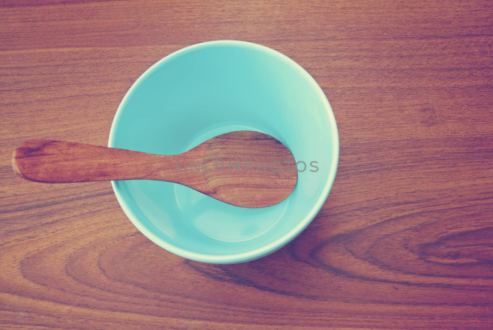 Blue bowl and wooden spoon on the table with retro filter effect by nuchylee