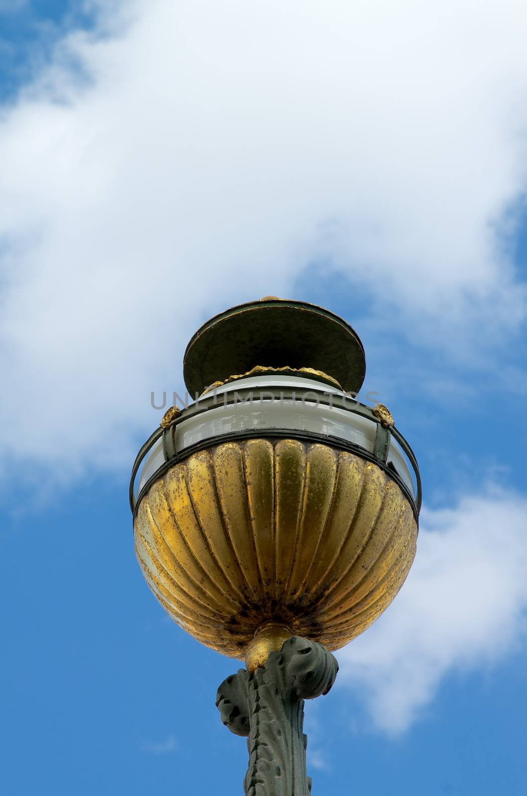 Old-fashioned Decorative Street Lantern with Gold Details on Blue and Cloudy background Outdoors