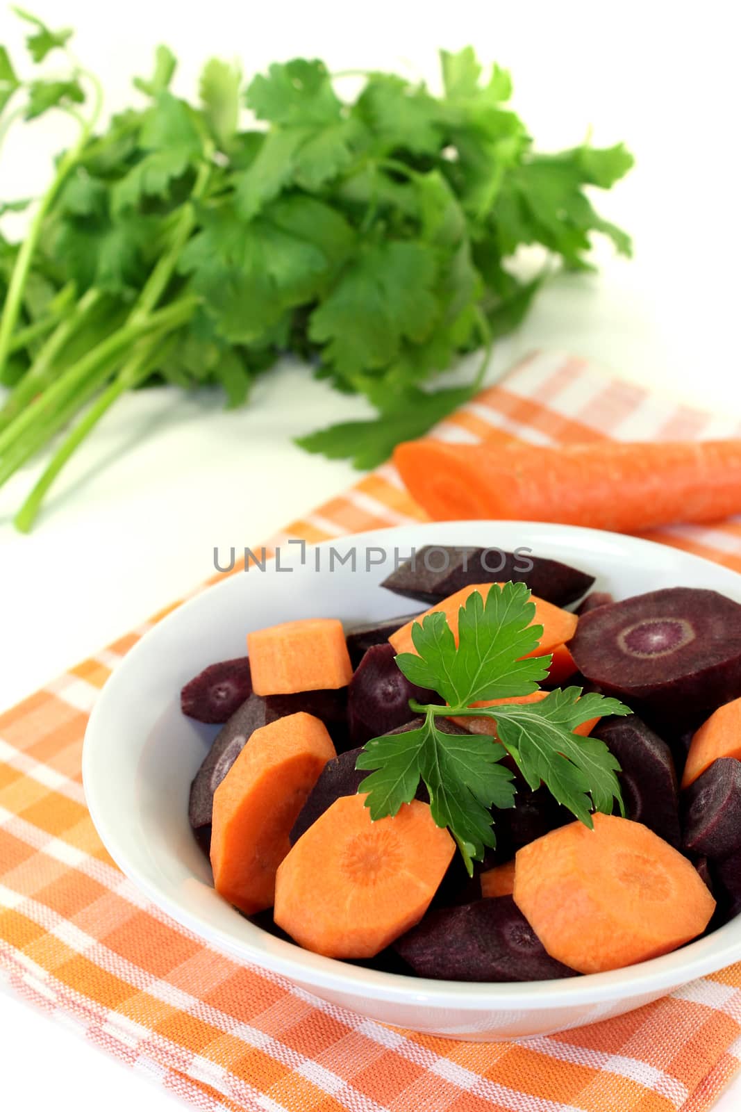 fresh sliced orange and purple carrots on a light background