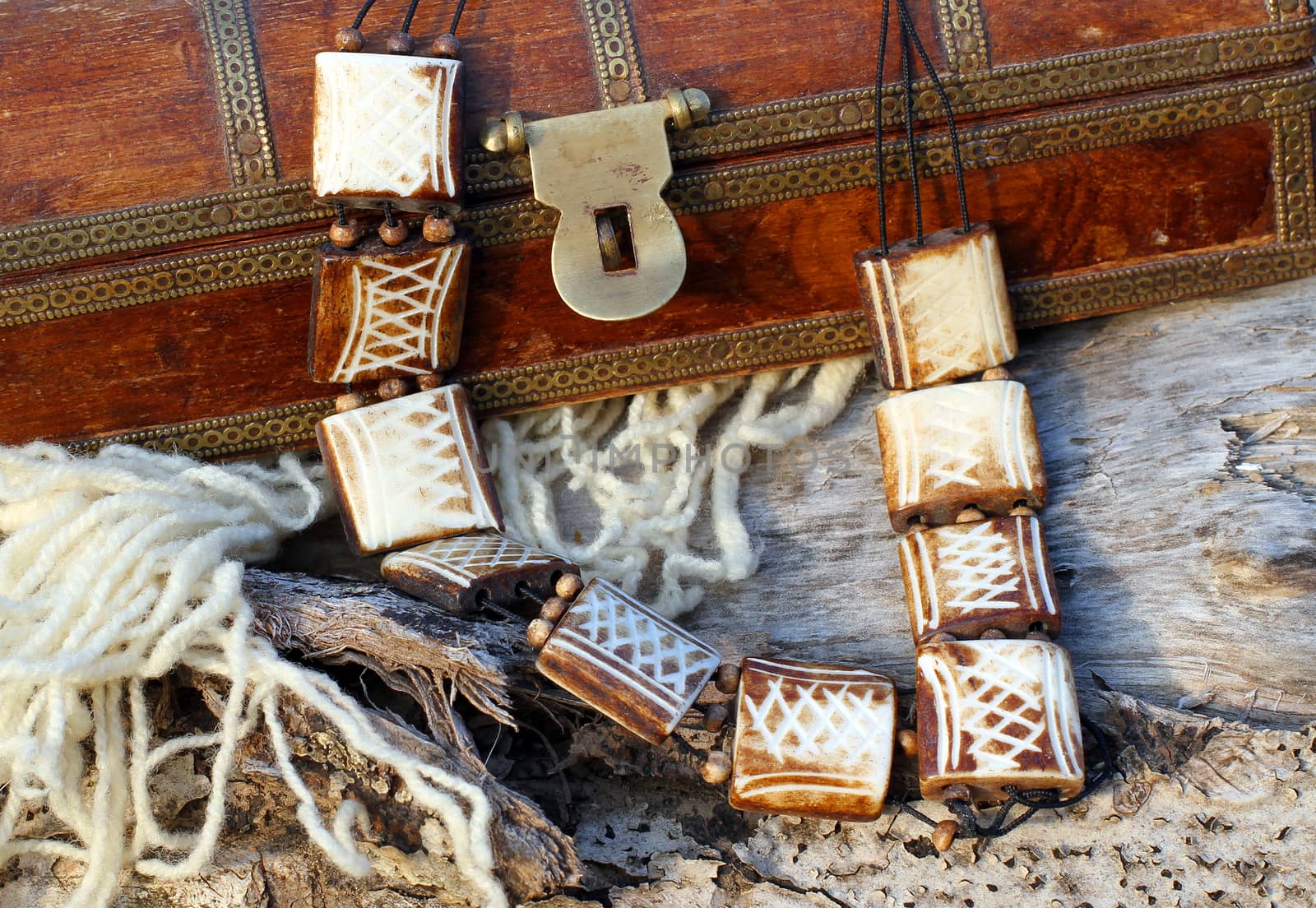 Ethnic handmade wooden necklace and old wooden chest on autumn-style background