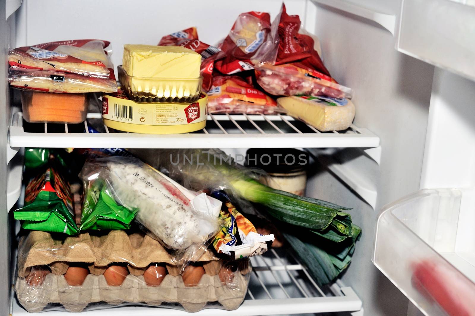 Open refrigerator containing food products each day as eggs, butter, cheese, sausage, meat and vegetables