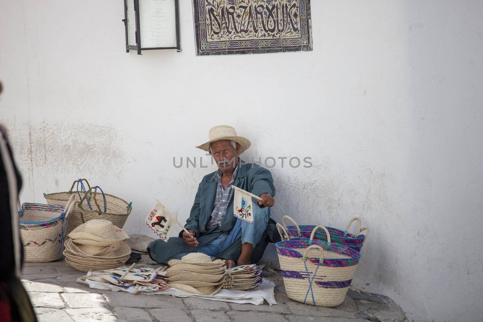 SIDI BOU SAID, TUNISIA, JUNE 19, 2012: Elder street vendor selling handmade Tunisian souvenirs from Africa.