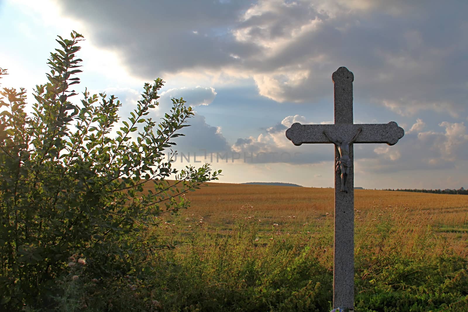 Photo shows details of countryside cross and landscape.