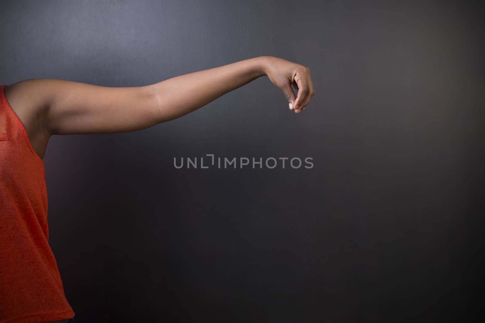 South African or African American woman teacher or student with hand pointing down on chalk black board background
