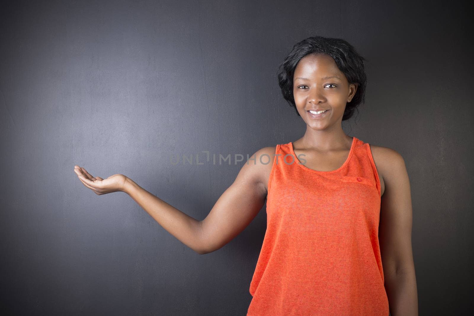 South African or African American woman teacher or student with hand out on chalk black board background