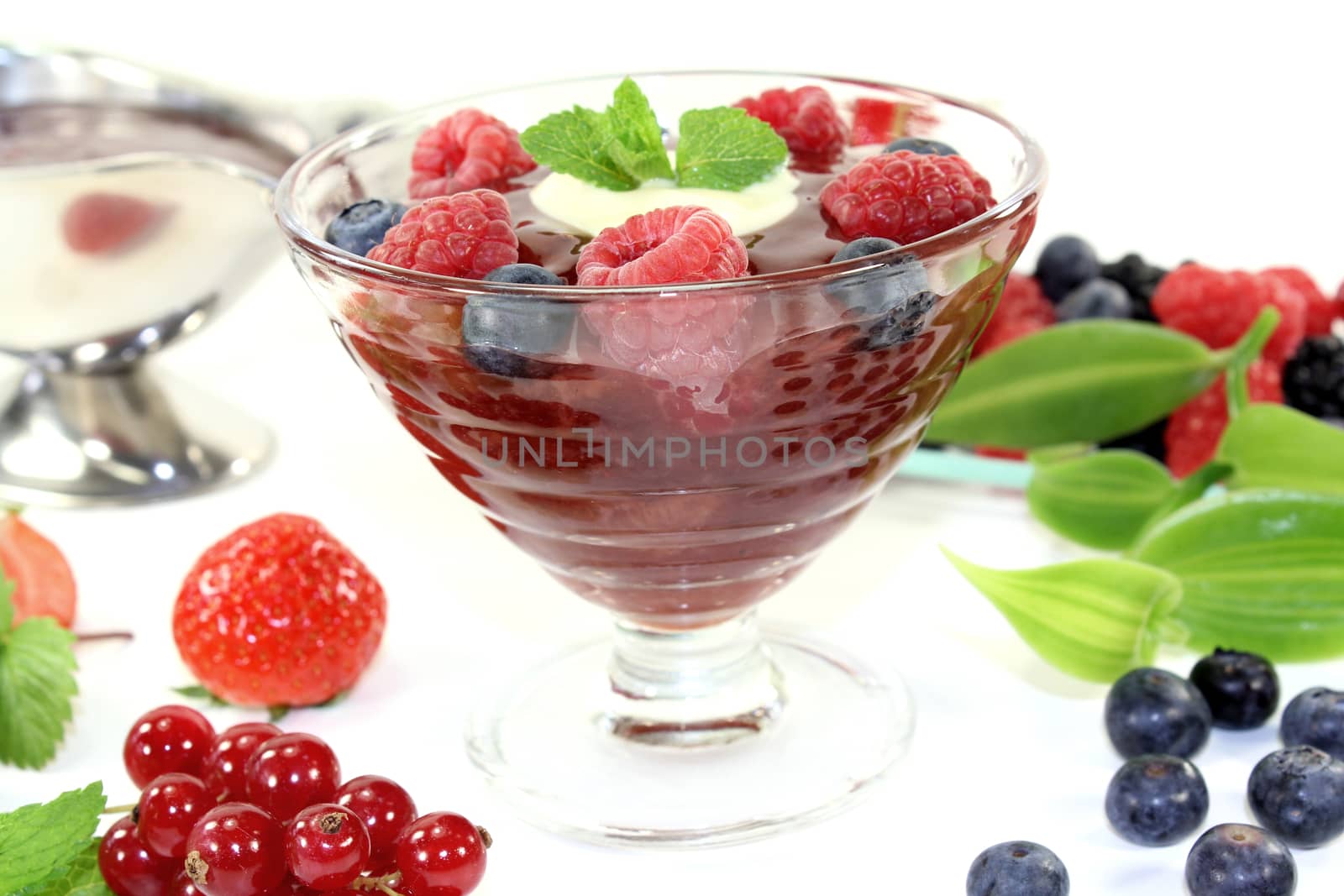 red fruit jelly with custard and raspberries on a light background