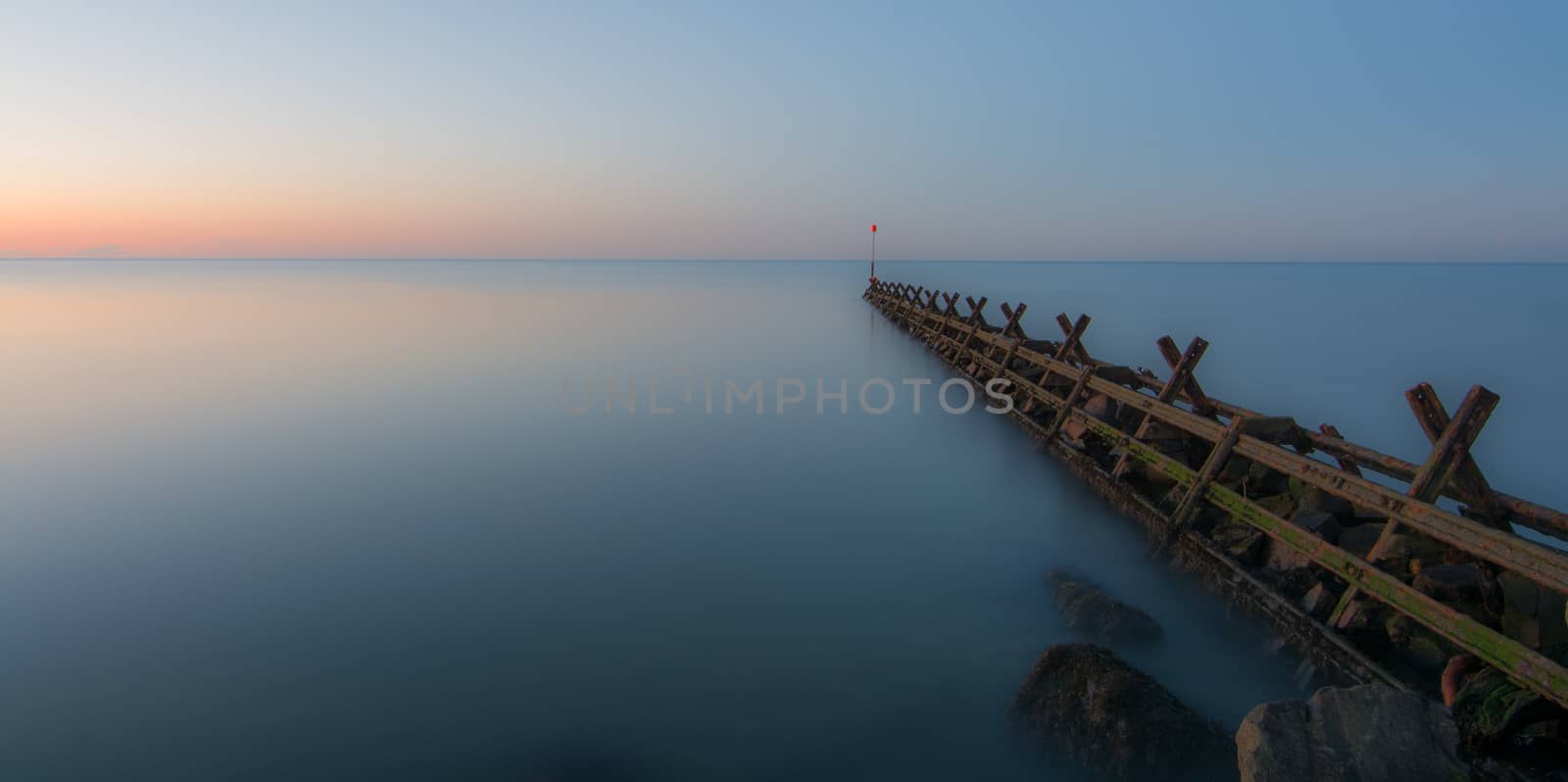 a breakwater, in a very calm sea, at sunset.  Long exposure.
