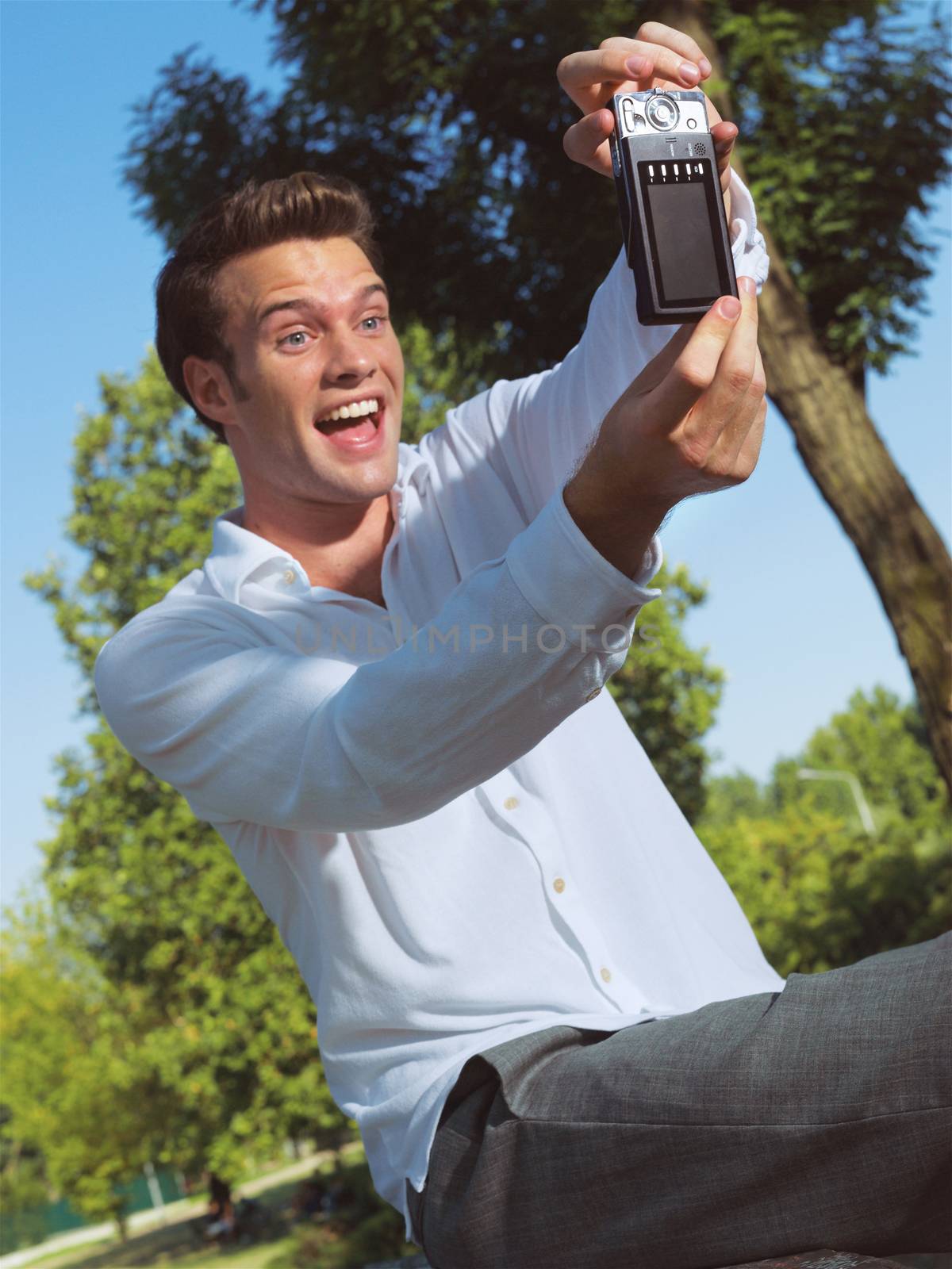 Handsome young guy taking photo with cellphone in park - Outdoor 