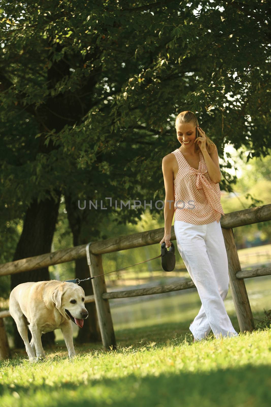 Young blond woman with mobile phone in the park 