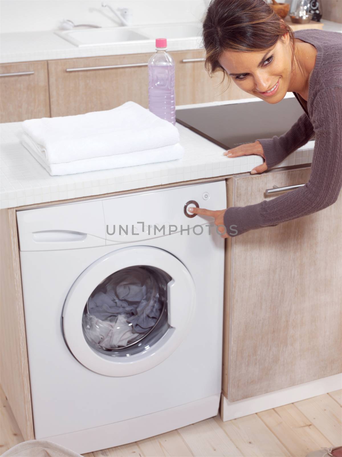 smiling female pressing a button on her washing machine 