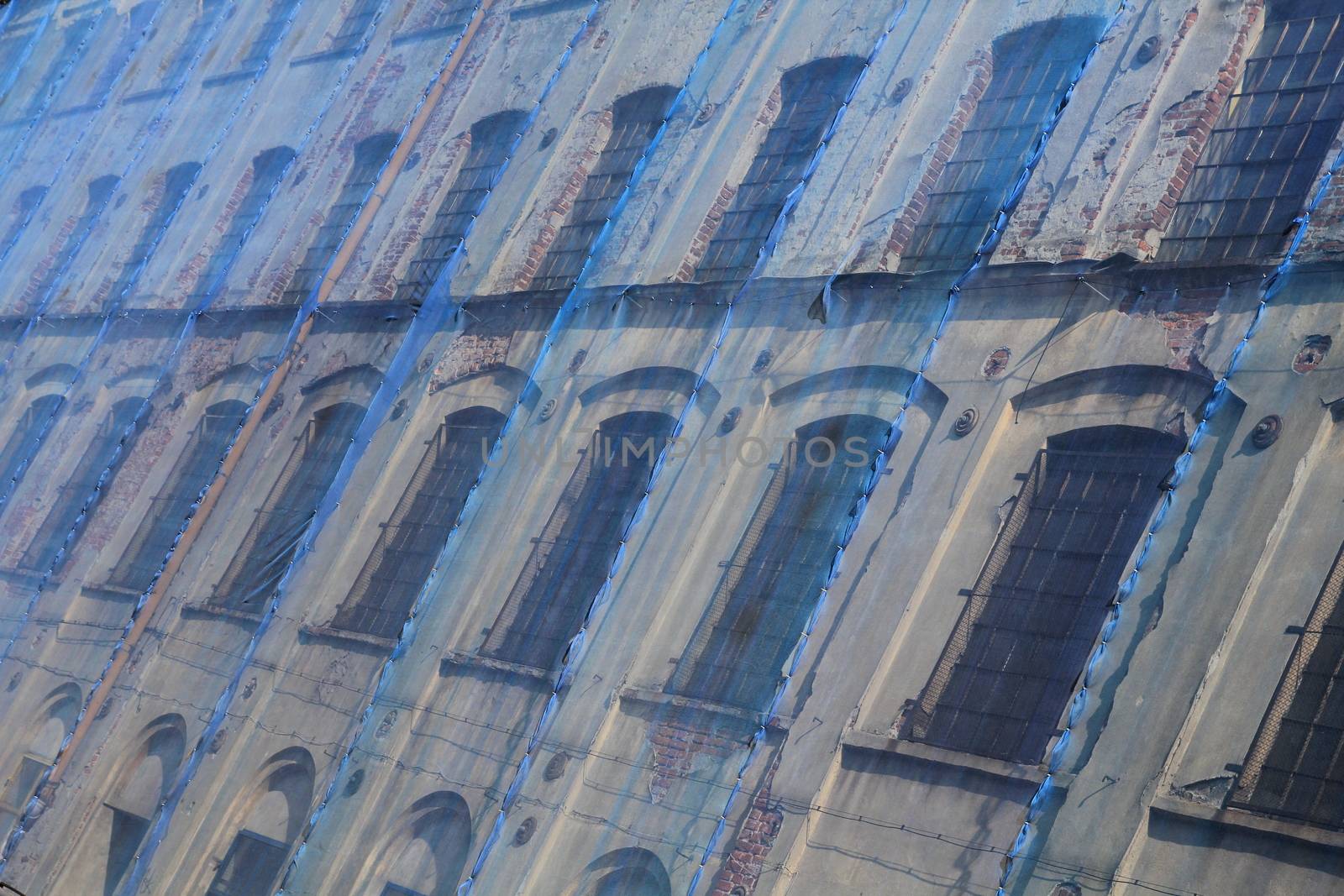 Facade of an old factory covered with protective blue mesh