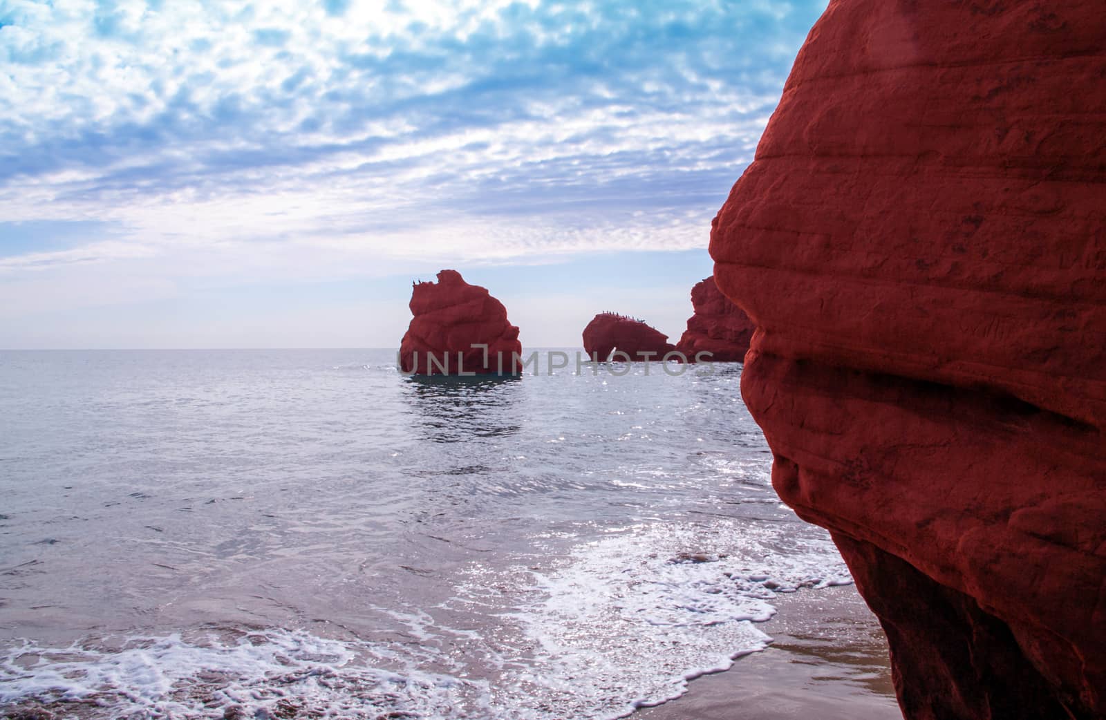 Wave on red cliffs at Dune de Sud