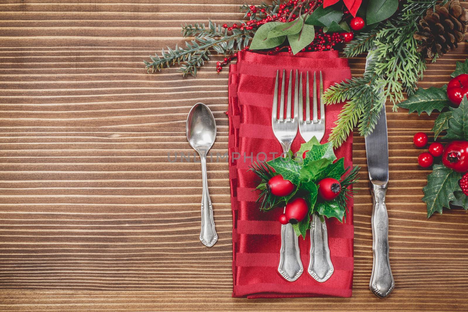 Christmas background with silverware and fir tree. A knife, spoon and two forks on a napkin on a textured tablecloth. Christmas vintage concept.